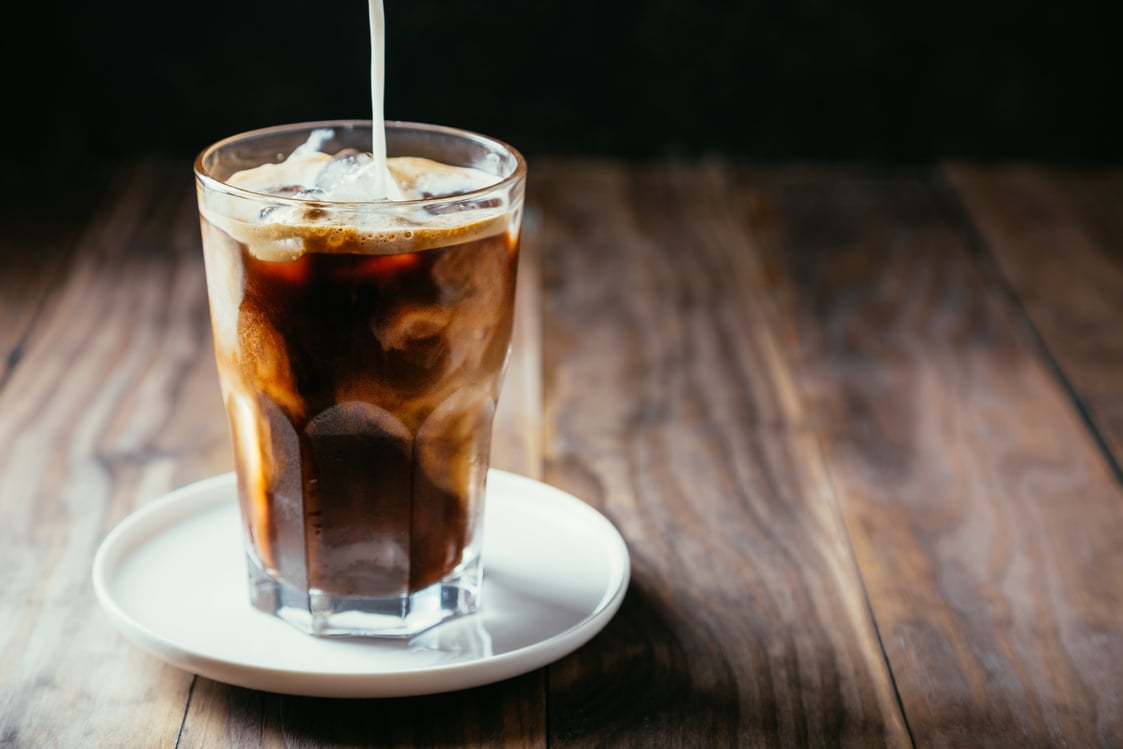 Pouring milk in an iced coffe